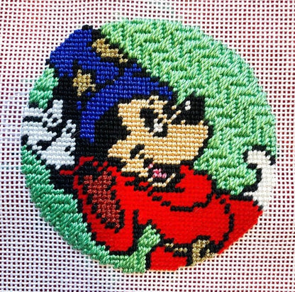 Cross-stitched design of iconic mouse character as a wizard on a green background.